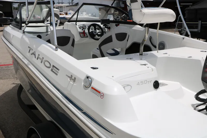 Slide: The Image of 2018 Tahoe 450 TF boat interior with steering wheel and seating, docked outdoors. - 13