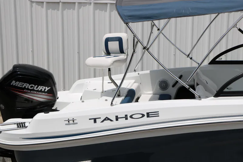 Slide: The Image of 2018 Tahoe 450 TF boat with Mercury engine and canopy, docked near a white wall. - 8