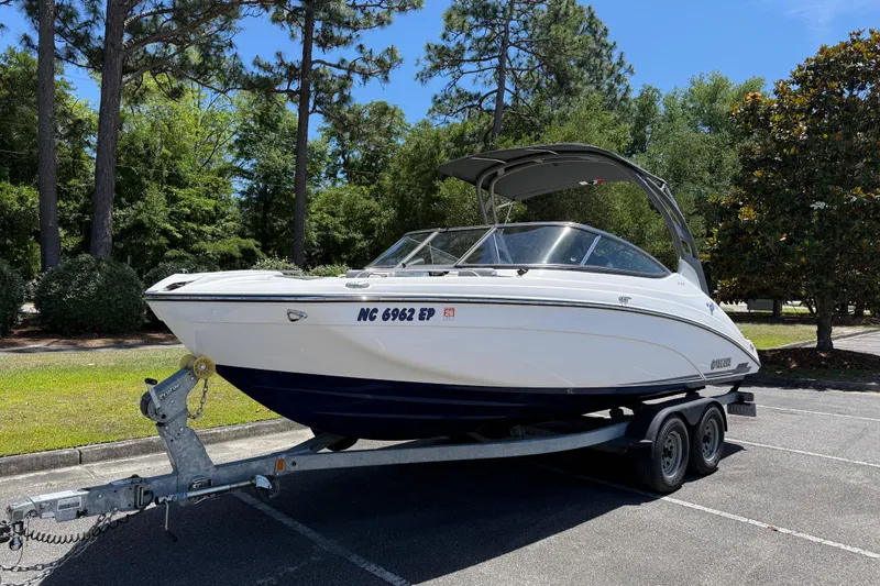 Slide: The Image of 2020 Yamaha Boats 212S on trailer, parked outdoors with trees in the background. - 2
