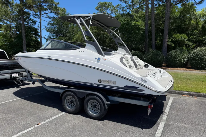 Slide: The Image of 2020 Yamaha Boats 212S on trailer in parking lot, surrounded by trees. - 3