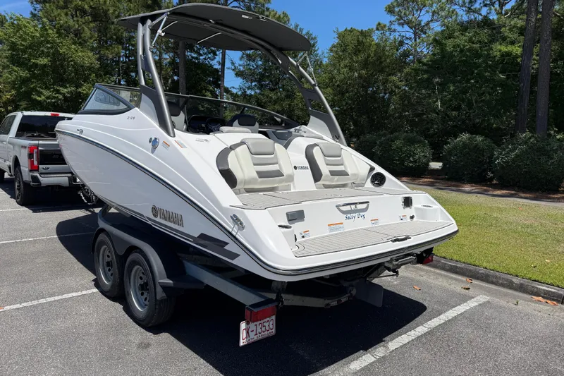 Slide: The Image of 2020 Yamaha Boats 212S on trailer in parking lot, surrounded by trees. - 4
