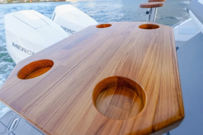 Slide: The Image of Wooden table with cup holders on a Hanover 387 boat, 2027 model, near water. - 31