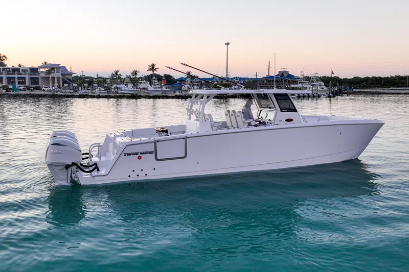 The Image of 2026 Twin Vee 400 GFX2 CC boat on calm water at sunset, near marina. - 1