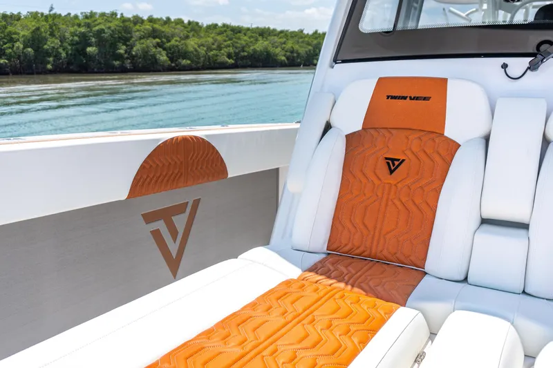 Slide: The Image of 2026 Twin Vee 400 GFX2 CC boat interior with orange and white seating, logo detail. - 22