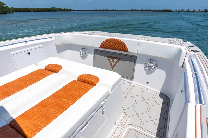 Slide: The Image of 2026 Twin Vee 400 GFX2 CC boat interior with orange and white seating, on calm water. - 27