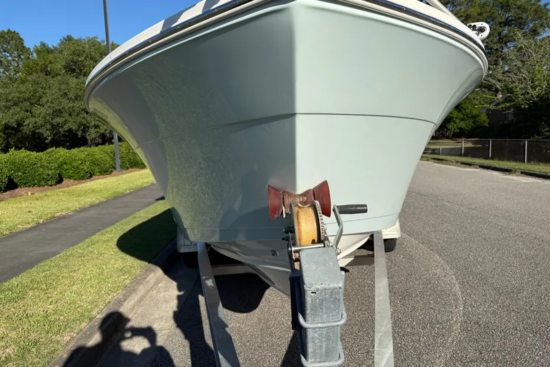 Slide: The Image of 2018 Cobia 220 Center Console boat on trailer, parked on a sunny street. - 10