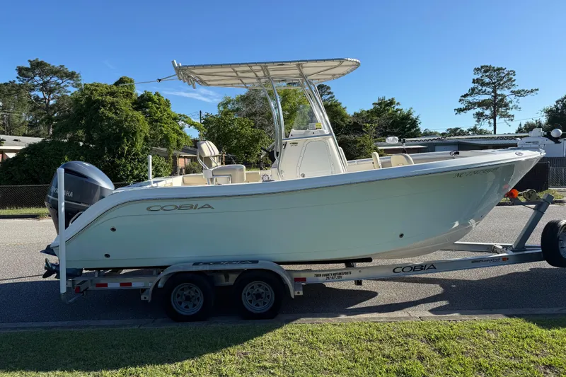 Slide: The Image of 2018 Cobia 220 Center Console boat on trailer, parked outdoors on a sunny day. - 7