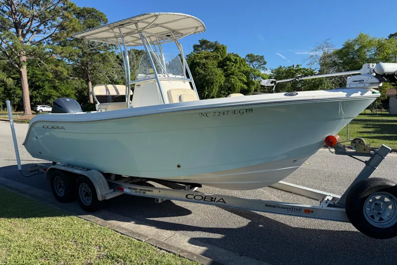 Slide: The Image of 2018 Cobia 220 Center Console boat on trailer, parked on a sunny street. - 8