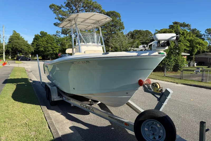 Slide: The Image of 2018 Cobia 220 Center Console boat on trailer, parked on a suburban street. - 9
