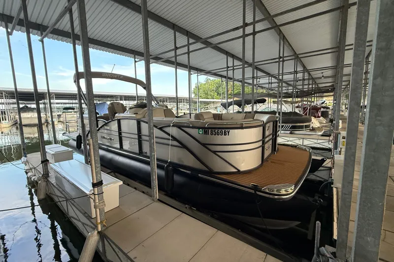 The Image of 2016 Starcraft MX 25 DL pontoon boat docked in a covered marina. - 1
