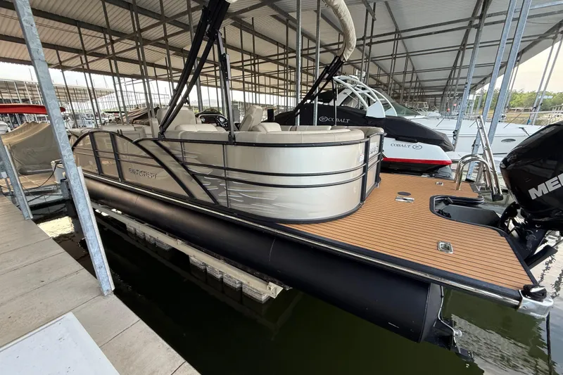 Slide: The Image of 2016 Starcraft MX 25 DL pontoon boat docked in a marina, featuring sleek design and spacious seating. - 5