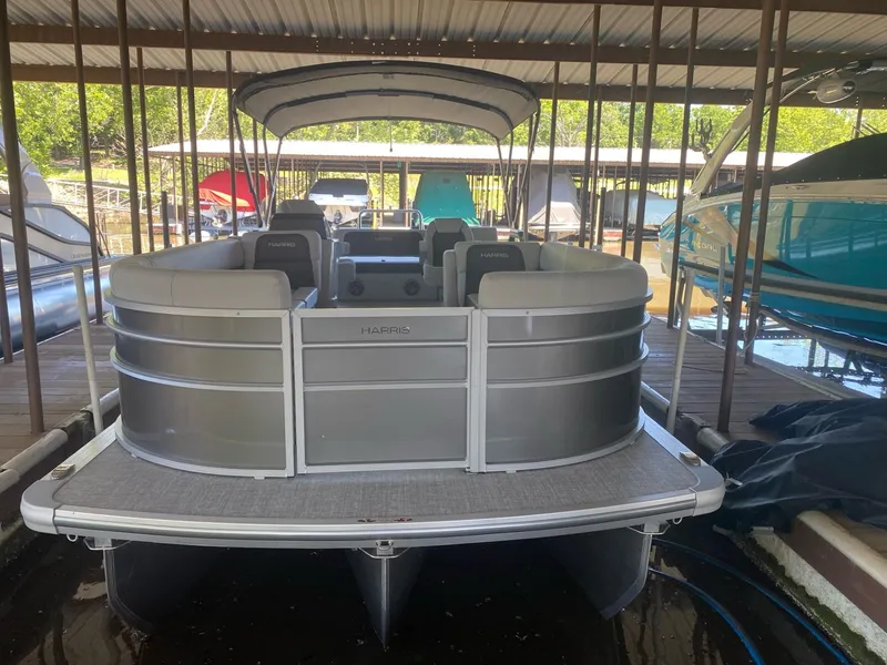 Slide: The Image of 2024 Harris 250CX pontoon boat docked, silver design. - 13