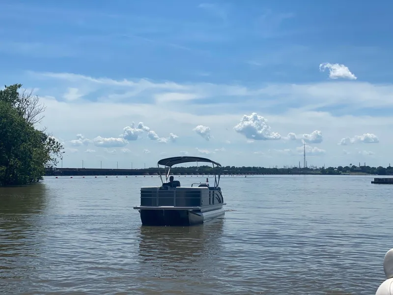 Slide: The Image of Harris 250CX pontoon boat 2024 on calm lake under blue sky. - 5
