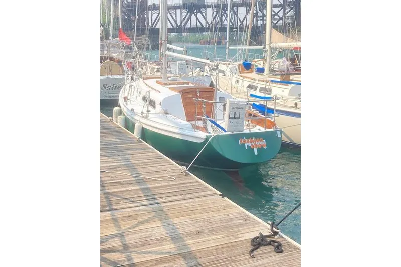 The Image of 1974 Ericson 32-2 sailboat docked at marina, featuring green hull and wooden deck. - 0