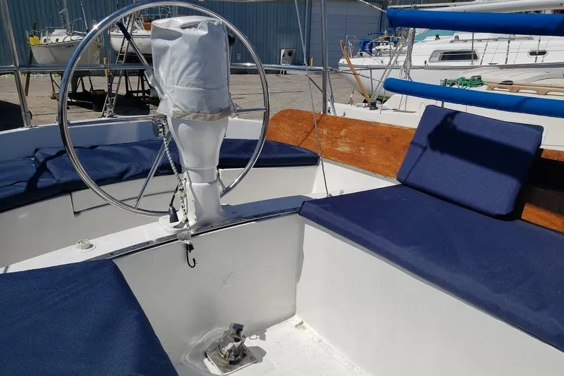 Slide: The Image of 1974 Ericson 32-2 sailboat cockpit with blue cushions and covered steering wheel. - 10