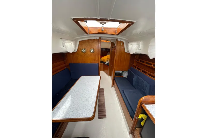 Slide: The Image of Interior of a 1974 Ericson 32-2 sailboat with wooden finishes and blue seating. - 14