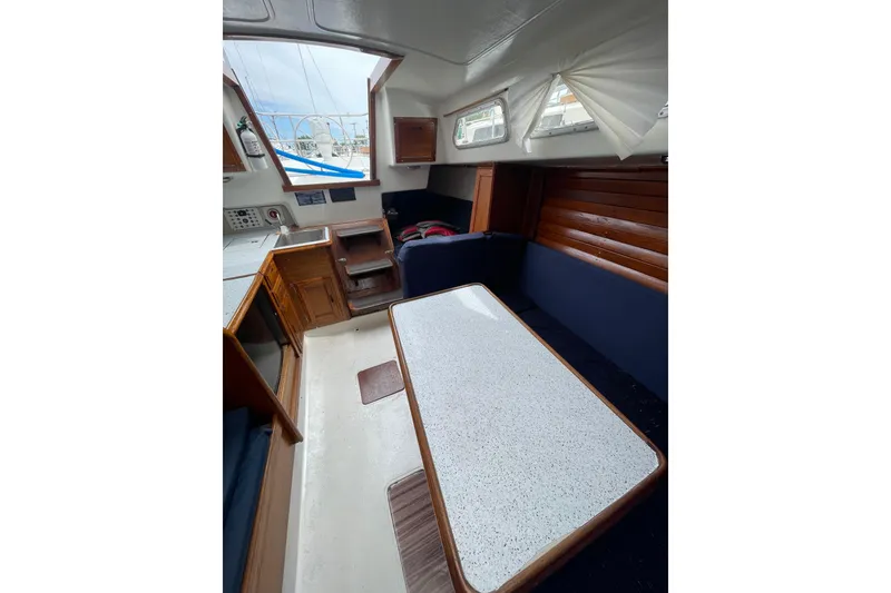 Slide: The Image of Interior of a 1974 Ericson 32-2 sailboat with a cozy dining area and wooden accents. - 17