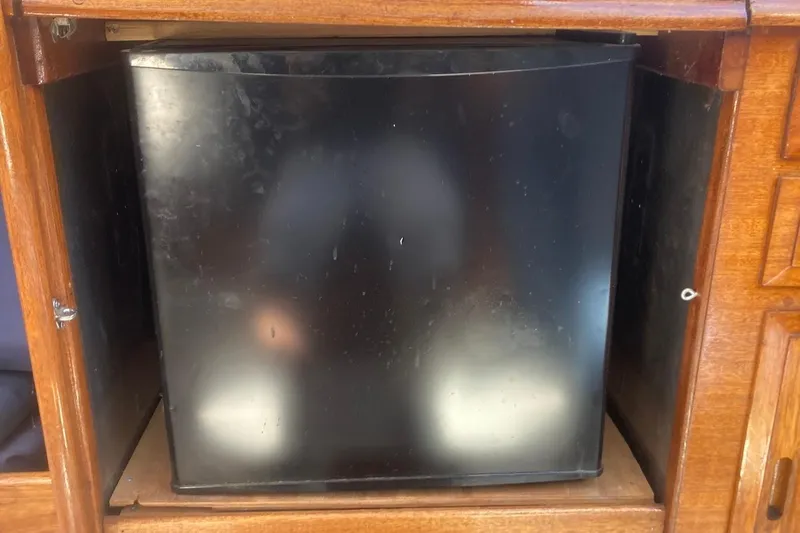 Slide: The Image of Black refrigerator inside wooden cabinet on a 1974 Ericson 32-2 sailboat. - 21