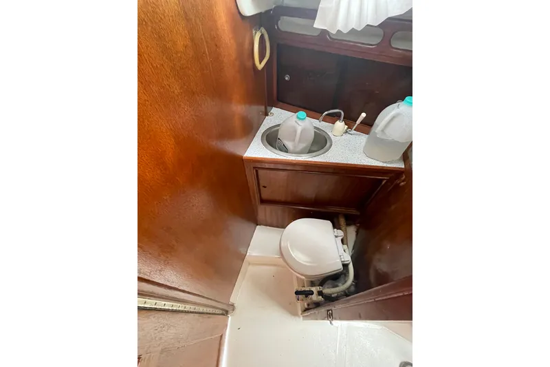 Slide: The Image of 1974 Ericson 32-2 sailboat bathroom with wooden interior, sink, and marine toilet. - 27