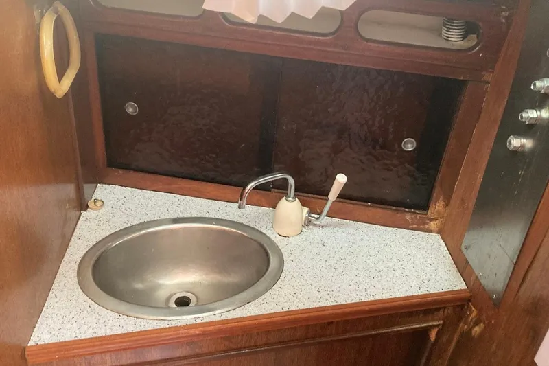 Slide: The Image of 1974 Ericson 32-2 yacht interior sink with wooden cabinetry and countertop. - 28