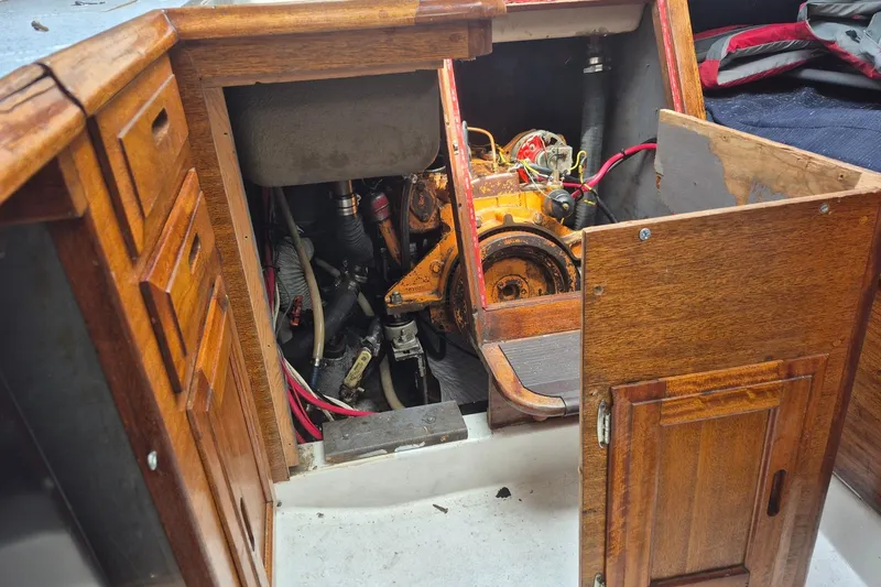 Slide: The Image of Engine compartment of a 1974 Ericson 32-2 sailboat, showcasing wooden cabinetry and mechanical components. - 29
