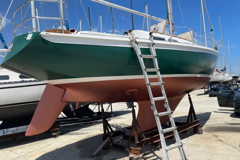 Slide: The Image of 1974 Ericson 32-2 sailboat on stands, green hull, ladder access, marina background. - 3