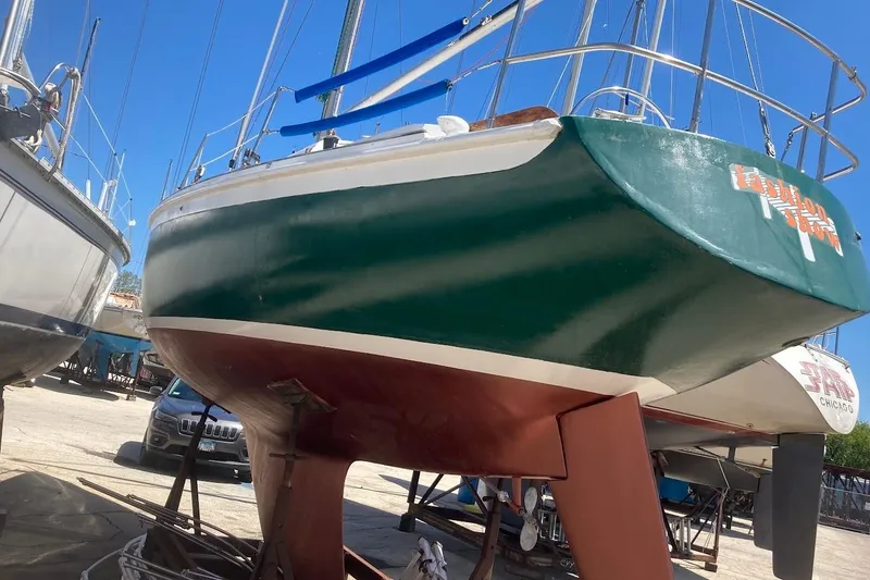 Slide: The Image of 1974 Ericson 32-2 sailboat on dry dock, green hull, blue sky background. - 7
