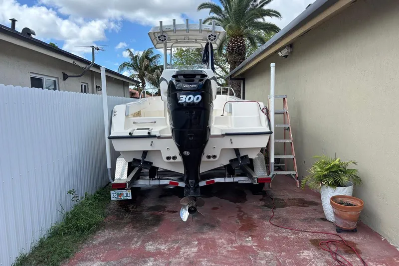 Slide: The Image of 2004 Key West 2220 Center Console boat with powerful outboard motor, parked beside a house. - 1