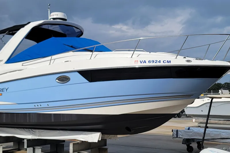 Slide: The Image of 2022 Monterey 295 Sport Yacht with blue cover, docked on land. - 70