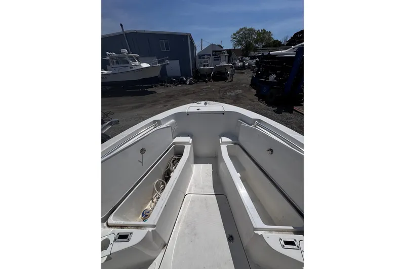 Slide: The Image of 2017 Release 210RX boat interior with open storage compartments, docked outdoors. - 25