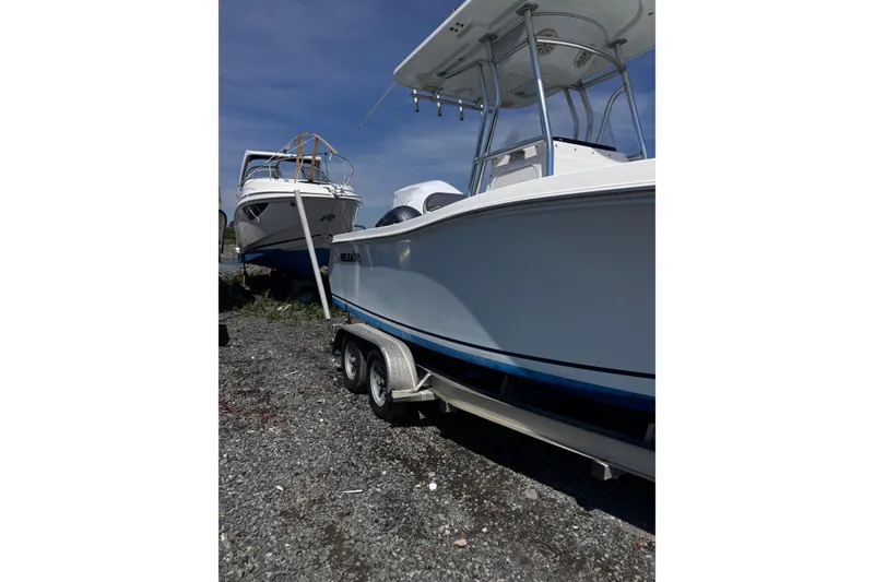 Slide: The Image of 2017 Release 210RX boat on trailer, parked on gravel, under clear blue sky. - 3