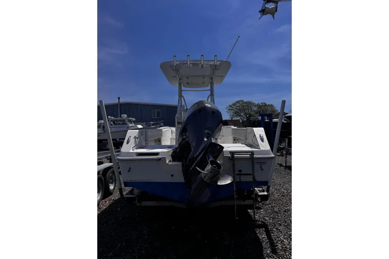 Slide: The Image of 2017 Release 210RX boat with outboard motor, parked on gravel under clear blue sky. - 5