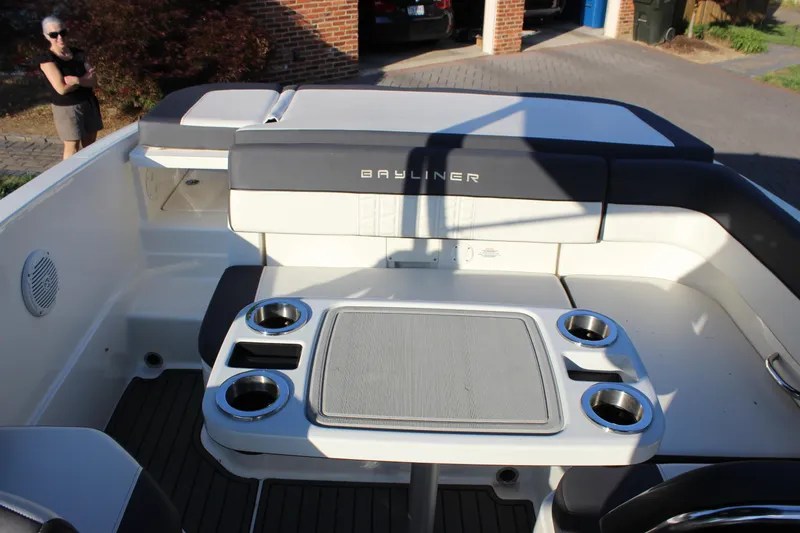 Slide: The Image of 2020 Bayliner VR6 Bowrider I/O interior with seating and table, parked in driveway. - 8
