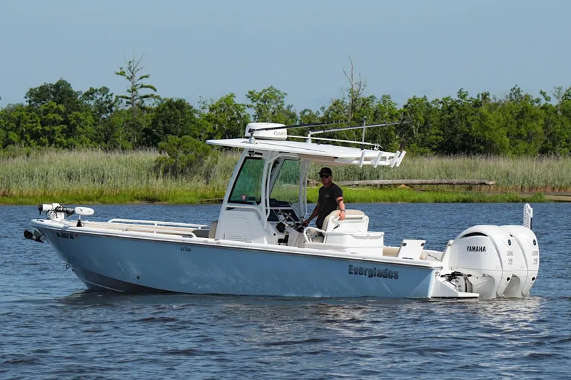 Slide: The Image of 2019 Everglades 273 Center Console boat on water with Yamaha engines, surrounded by greenery. - 12