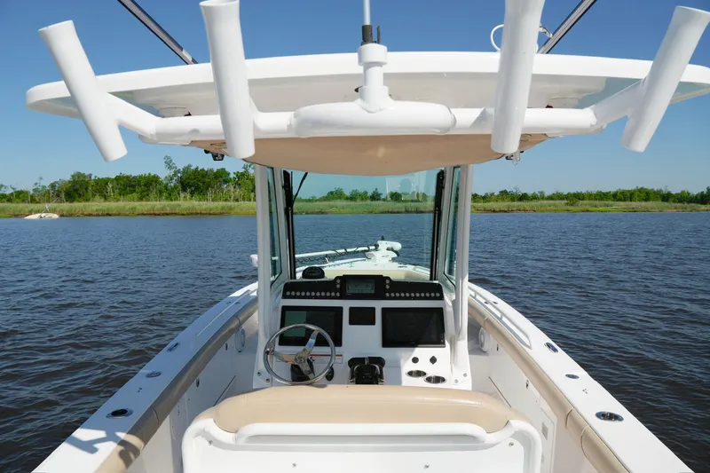 Slide: The Image of 2019 Everglades 273 Center Console boat on calm water, featuring helm and rod holders. - 19