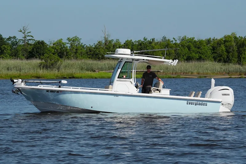 Slide: The Image of 2019 Everglades 273 Center Console boat on water with Yamaha engine, surrounded by greenery. - 4