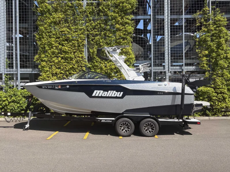 The Image of 2022 Malibu M220 boat on trailer with green backdrop. - 1