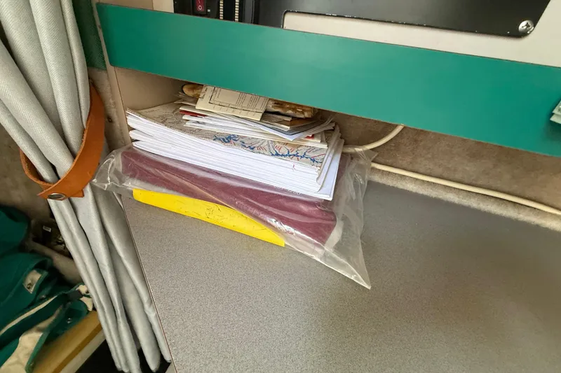 Slide: The Image of Stack of papers and maps on a shelf inside a 1988 Cruisers Yachts 2470 Holiday. - 14
