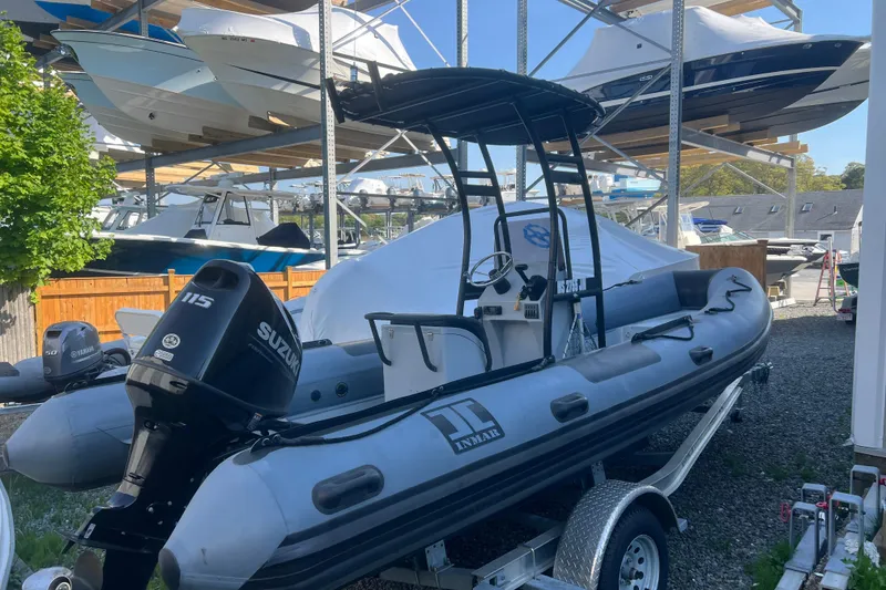 Slide: The Image of 2023 Inmar 600R-PT inflatable boat with Suzuki 115 engine on trailer in marina. - 1
