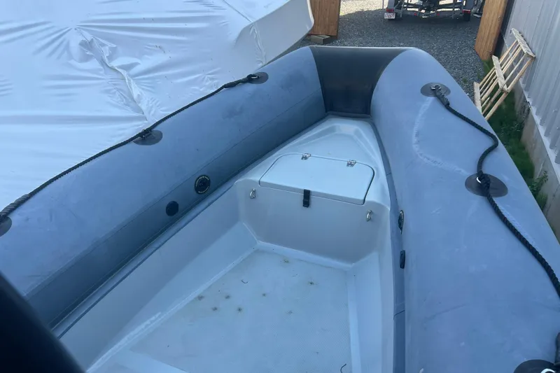 Slide: The Image of 2023 Inmar 600R-PT inflatable boat interior with storage compartment, docked outdoors. - 14