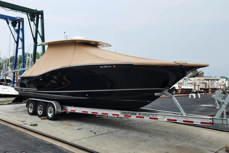 Slide: The Image of 2015 Scout 320 LXF boat on trailer at marina, covered with tan canopy. - 12
