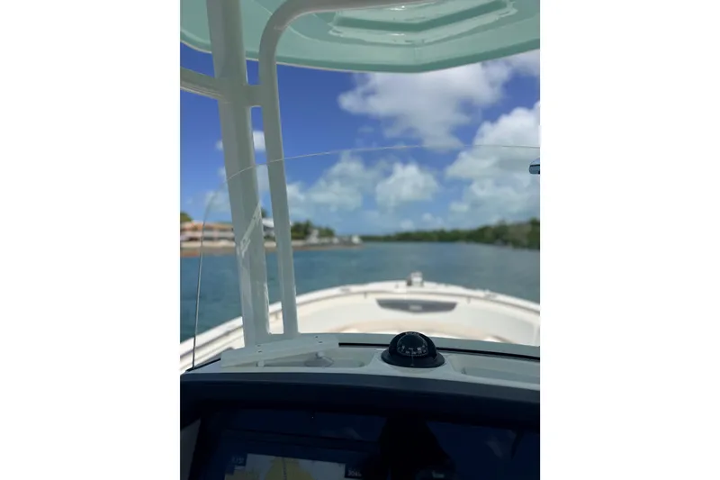 Slide: The Image of 2019 Robalo R242 Center Console boat navigating a scenic waterway under a clear blue sky. - 13