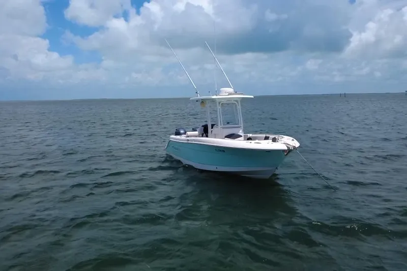 Slide: The Image of 2019 Robalo R242 Center Console boat anchored on calm ocean waters under a cloudy sky. - 18