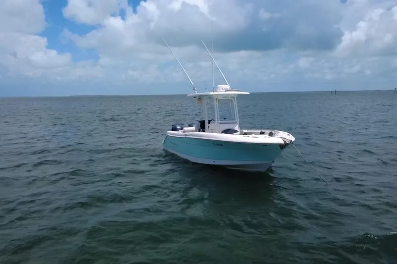 Slide: The Image of 2019 Robalo R242 Center Console boat anchored on calm ocean waters under a cloudy sky. - 20