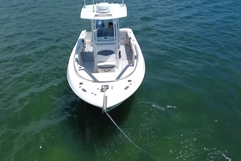Slide: The Image of 2019 Robalo R242 Center Console boat anchored on calm green water. - 23