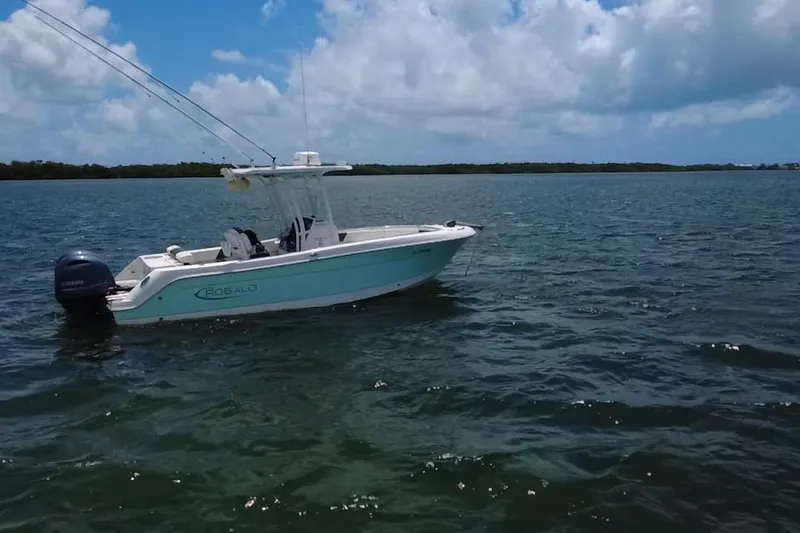 Slide: The Image of 2019 Robalo R242 Center Console boat on calm water under blue sky. - 28