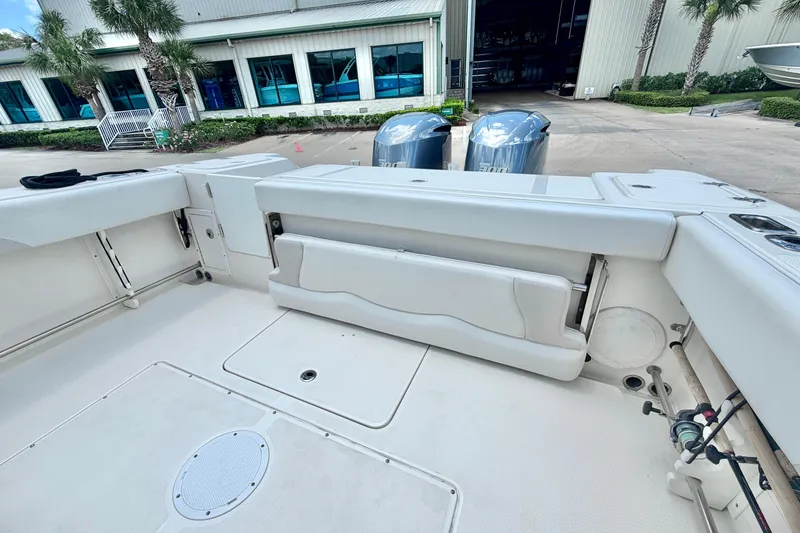 Slide: The Image of 2013 Edgewater 318CC boat interior with seating and twin engines, docked near a building. - 13