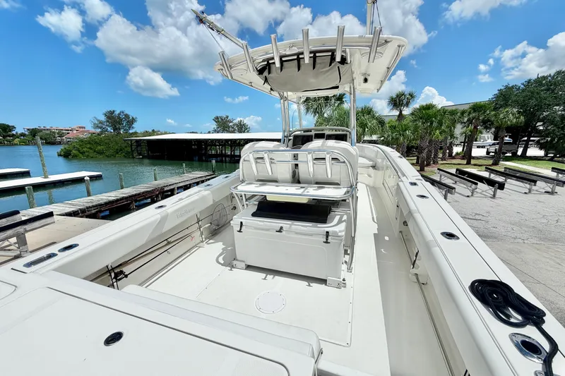 Slide: The Image of 2013 Edgewater 318CC boat docked by a scenic waterfront under a clear blue sky. - 2