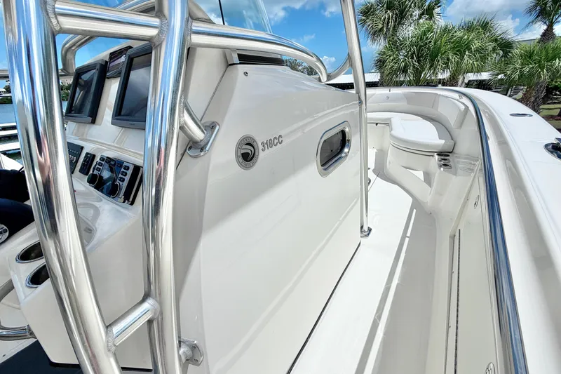 Slide: The Image of 2013 Edgewater 318CC boat interior with control panel and seating, under clear blue sky. - 20