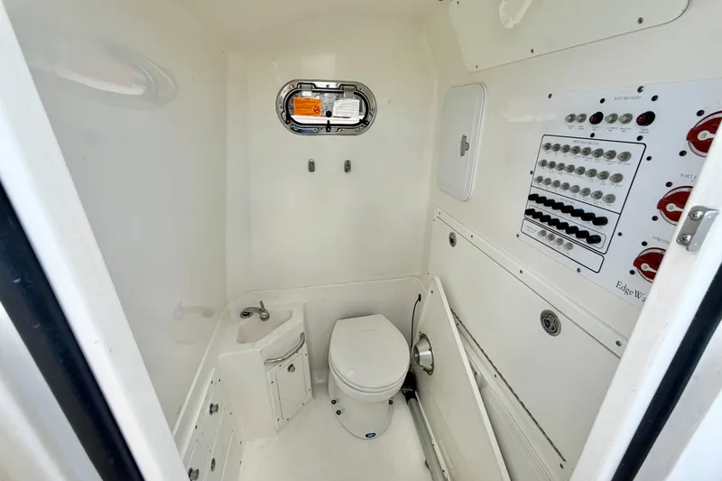 Slide: The Image of Interior of 2013 Edgewater 318CC boat featuring a compact bathroom with control panel. - 21